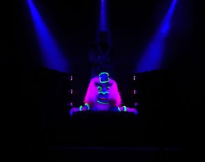 A wild looking glow-in-the-dark puppet crouching on stage