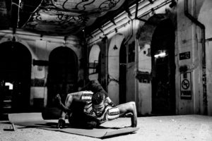 a circus performer stretches on a yoga mat in a warehouse