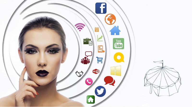 A circus artist in bold stage makeup surrounded by a cloud of social media icons