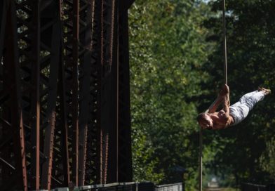 A man performs a back lever on aerial rope