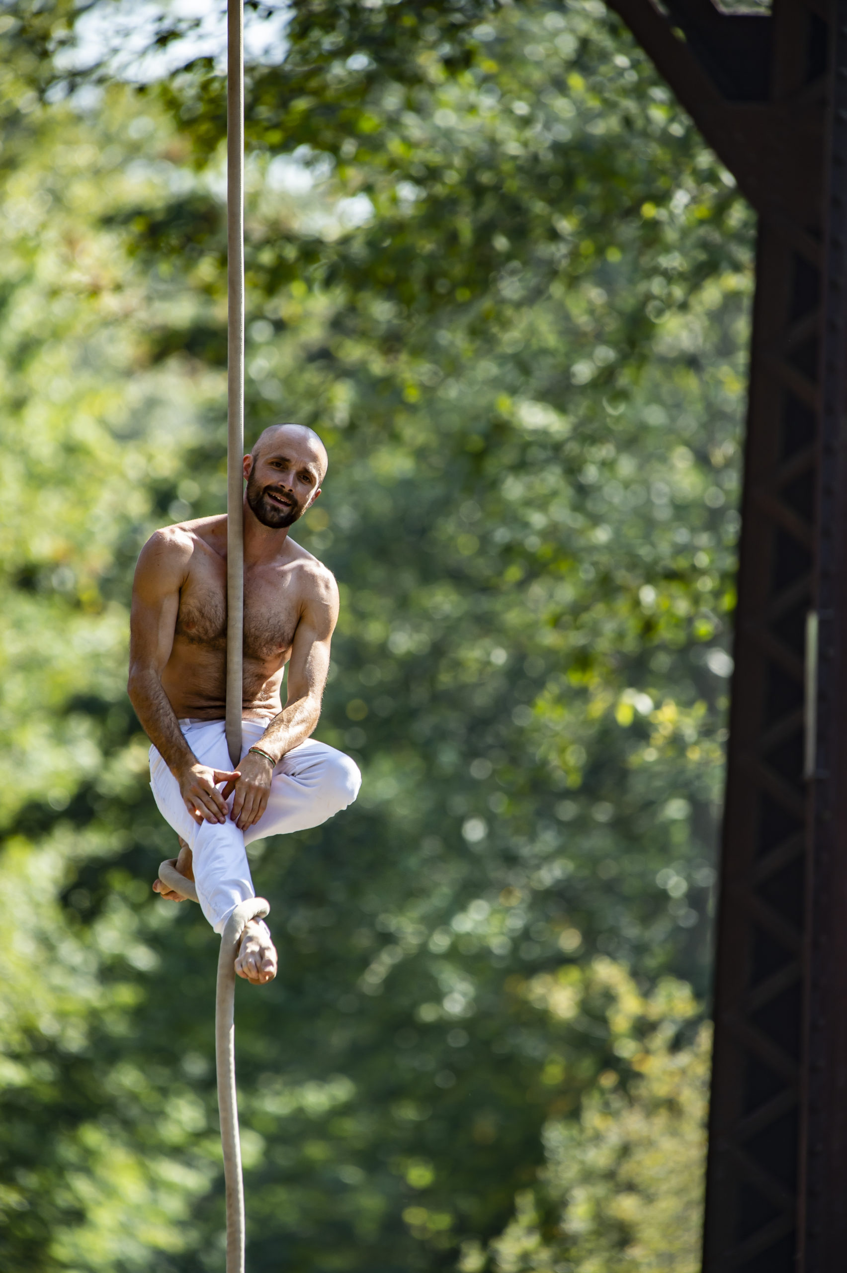 Terry Crane hangs in a relaxed seated position with one leg and one foot wrapped on the vertical rope