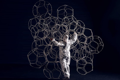 An artist stands surrounded by repeated shapes