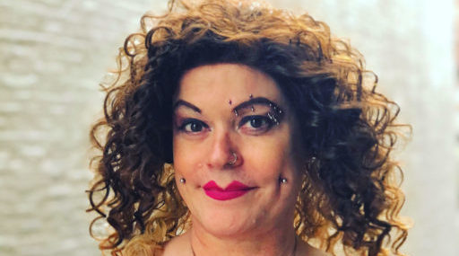 a trans woman circus performer with curly brown hair, facial piercings and red lipstick
