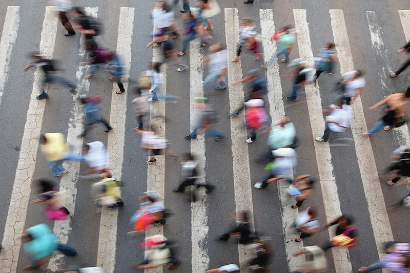 An aerial shot of a crowd of people walking through a street