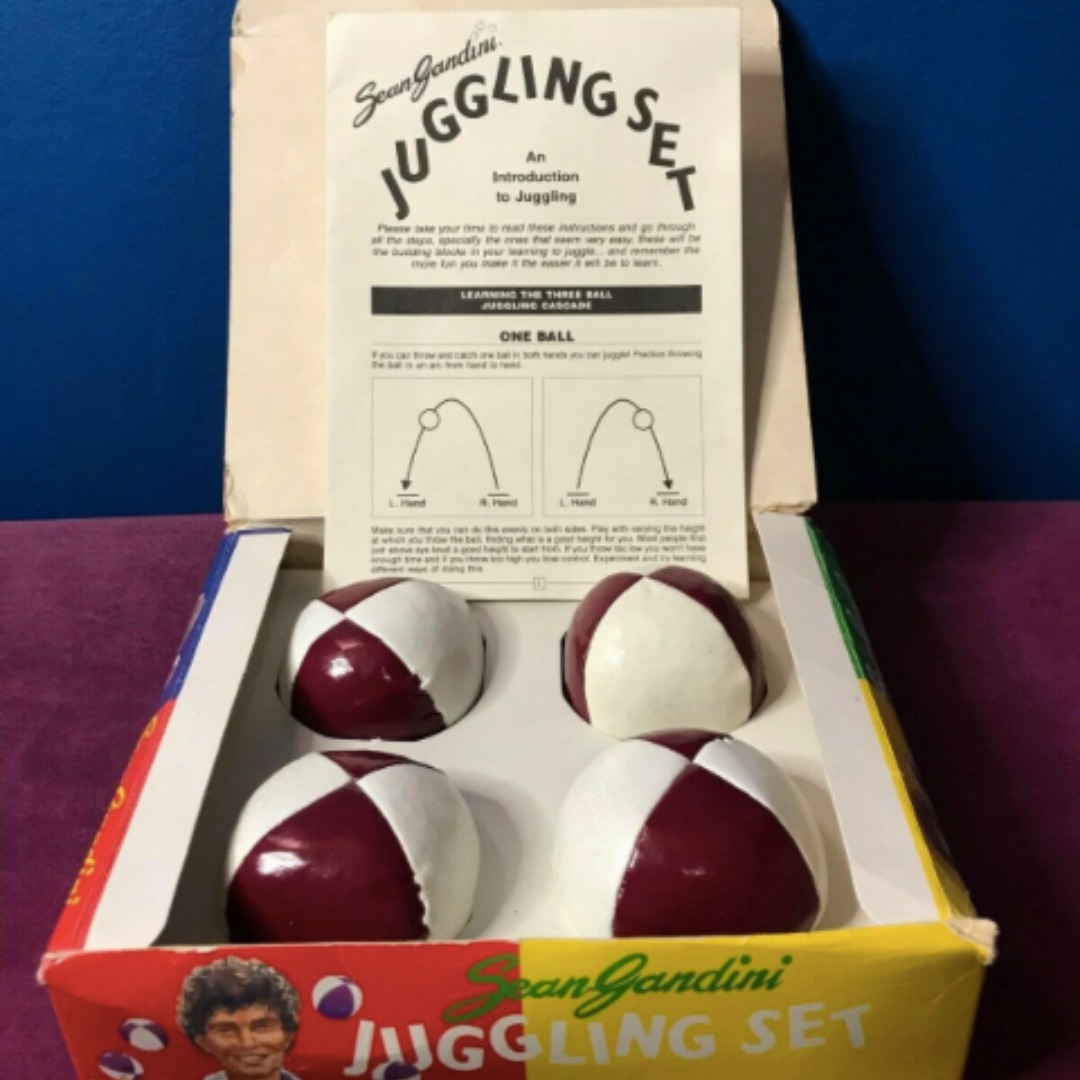 An opened Sean Gandini juggling kit, with an instruction sheet and four red-and-white beanbags