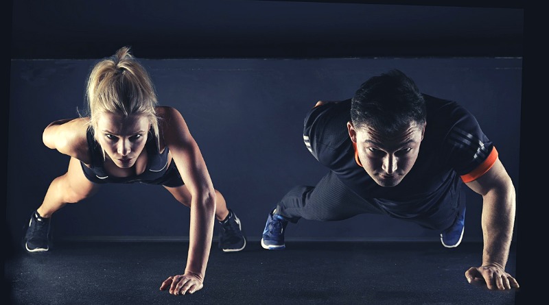 male and female athletes or circus performers train by doing pushups