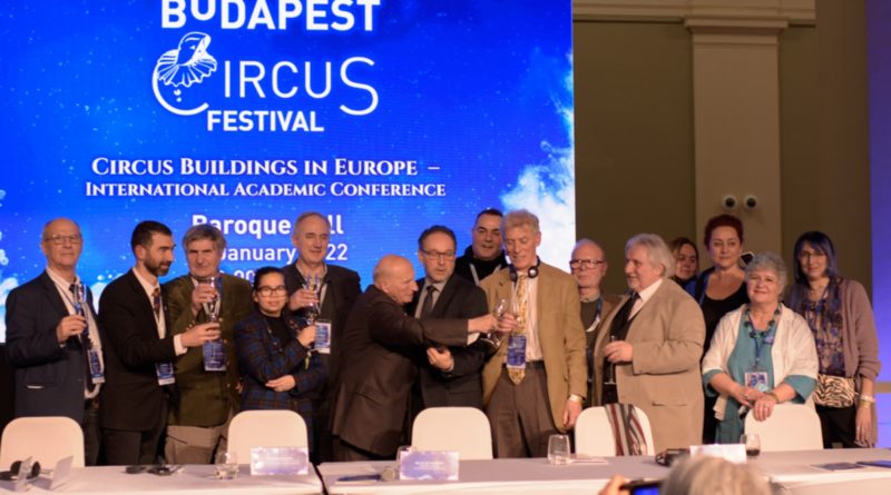 At the Circus Buildings in Europe Conference, a panel of circus history experts stands in front of a Budapest Circus Festival banner