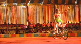 A Rayman Circus performance in New Delhi, 2015. Female unicyclist in the circus ring rides with a smile