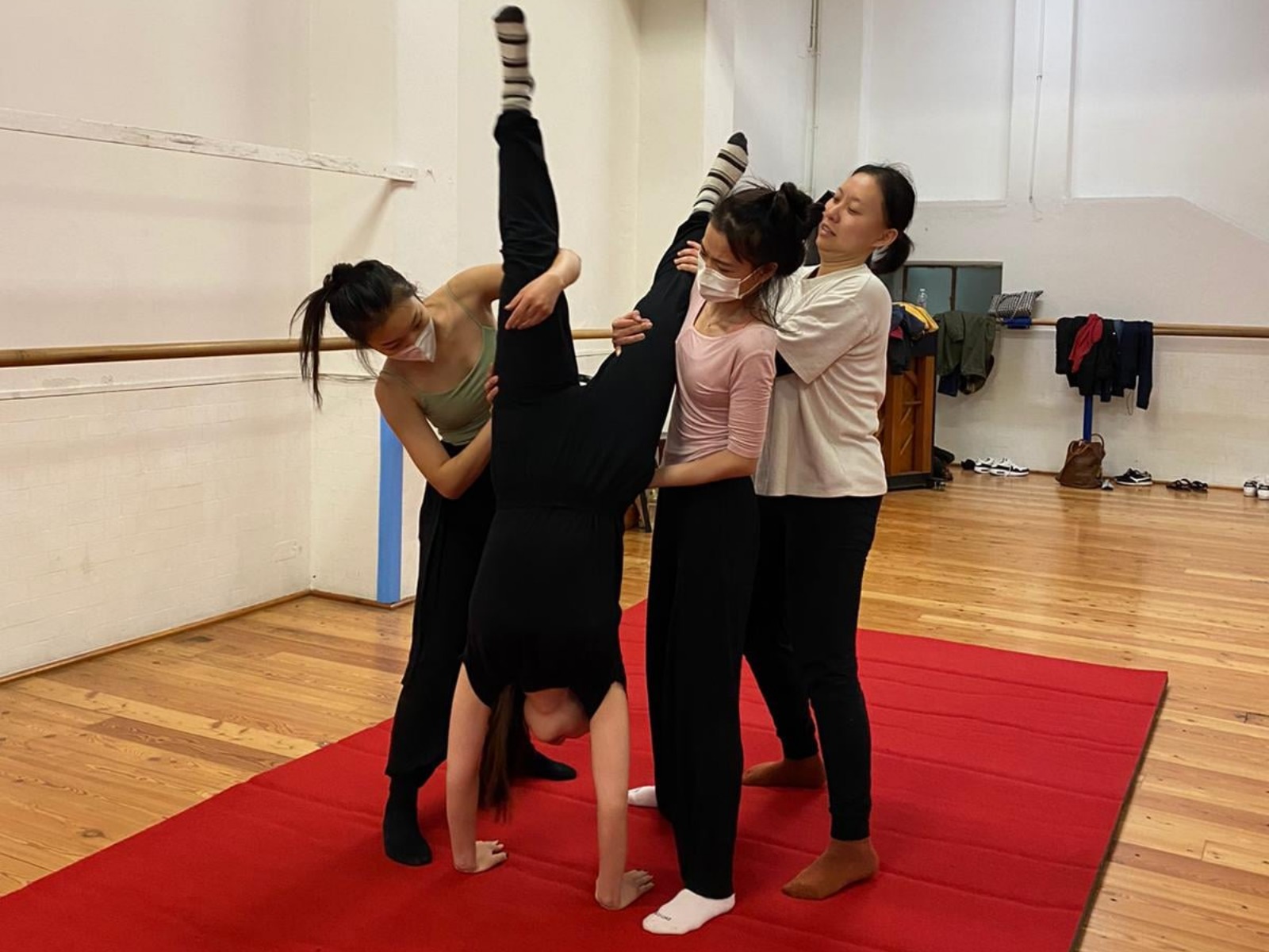 Three Palestine Circus School students guide a classmate to a handstand