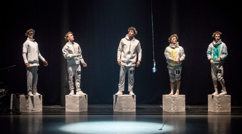 Cast of the Barely Methodical Troupe in KIN. The five performers wear sweatshirts and stand on block-shaped platforms