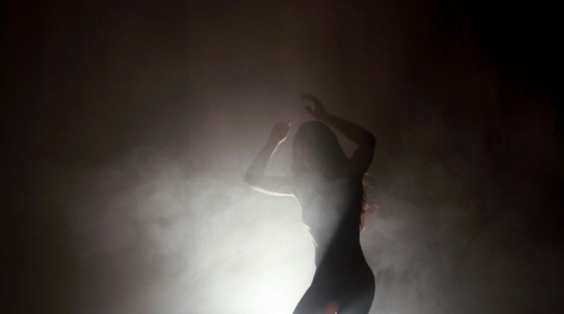Performer Zinnia Oberski in Dreams of the Small Gods. As Wild Woman, Zinnia dances under smoky stage lighting