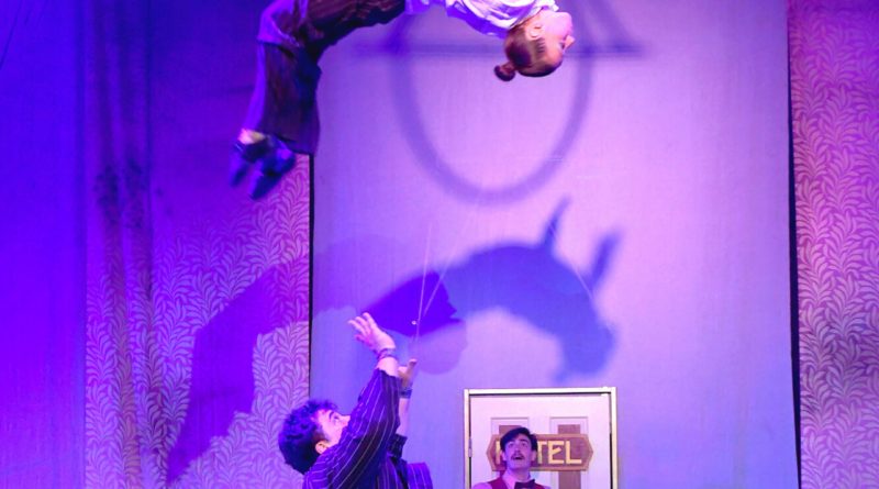 Lost in Translation circus show, "Hotel Paradiso." Acrobat in business suit throws another acrobat in the air.