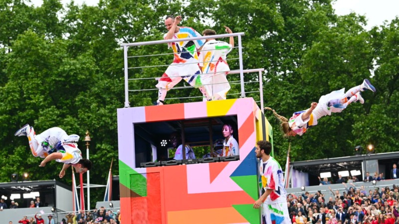 Cirque Bijou acrobats perform around a colorful parade float cutout
