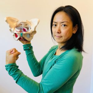 Mayumi Yamamoto, Japanese female athletic trainer, poses with a model of a pelvic bone
