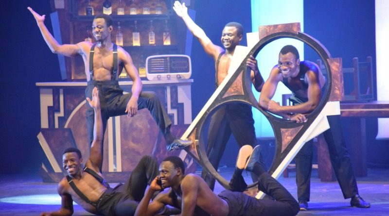 The Black Blues Brothers acrobatic troupe at Edinburgh Fringe 2019. Five Kenyan male acrobats in dress pants and suspenders pose around a mirrored prop