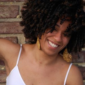 Shavon Norris, choreographer, dancer, and awardee of the Almanac Dance Circus Theatre BIPOC New Work award. Shavon is a young Black woman with an afro and large golden earrings