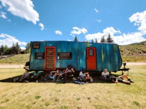 Students in Flynn Creek Circus mentorship program sit together outside of their blue camper