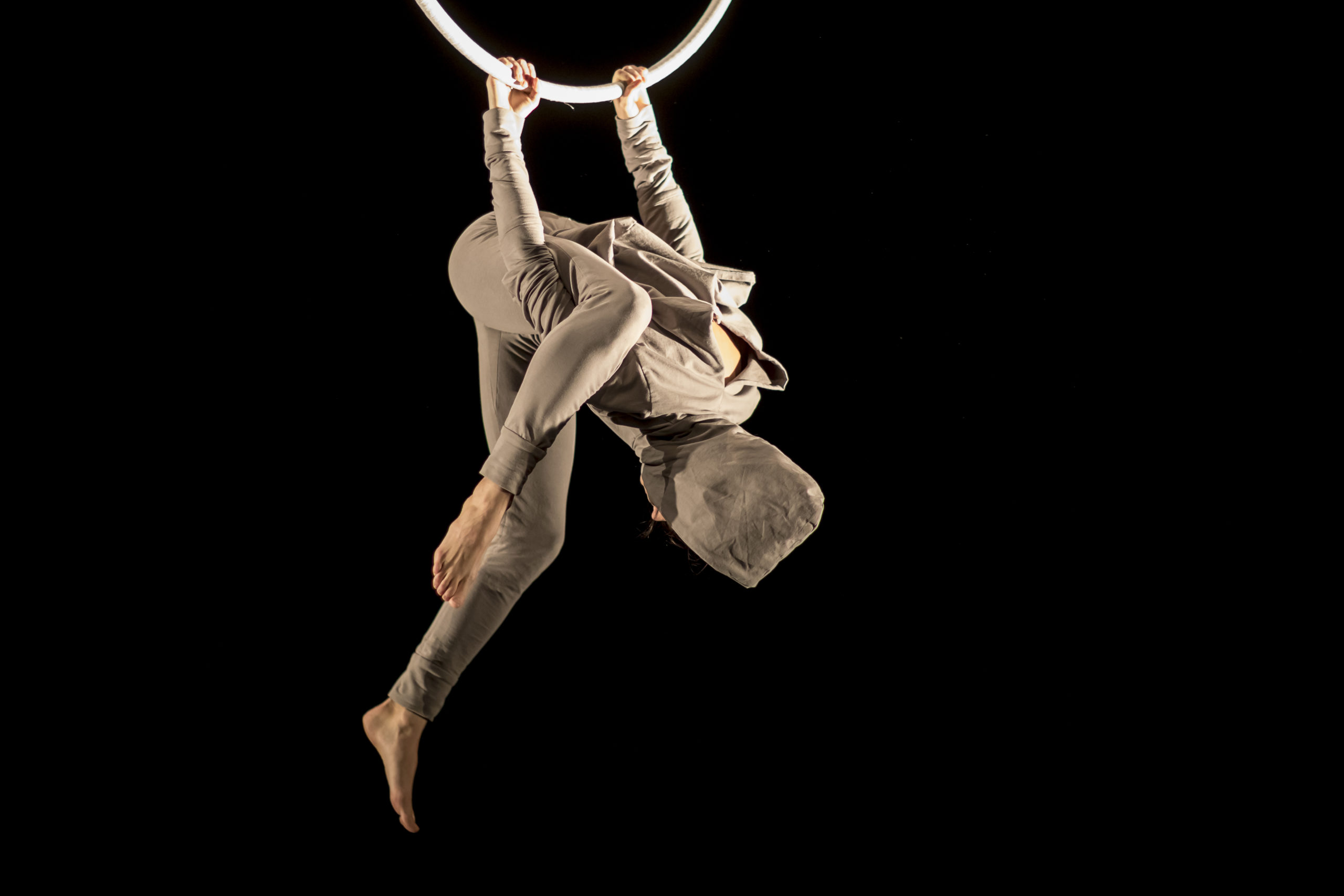 Czech aerialist Klára Hajdinová hangs from a ring. Her face is covered.