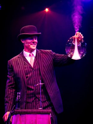 In Spiegelworld's Opium, circus performer Denis Lock holds a bubble blown around a test tube