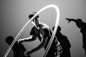 Taiwanese circus artist Chao Wei Chen performs cyr wheel against a background of shadowed silhouettes