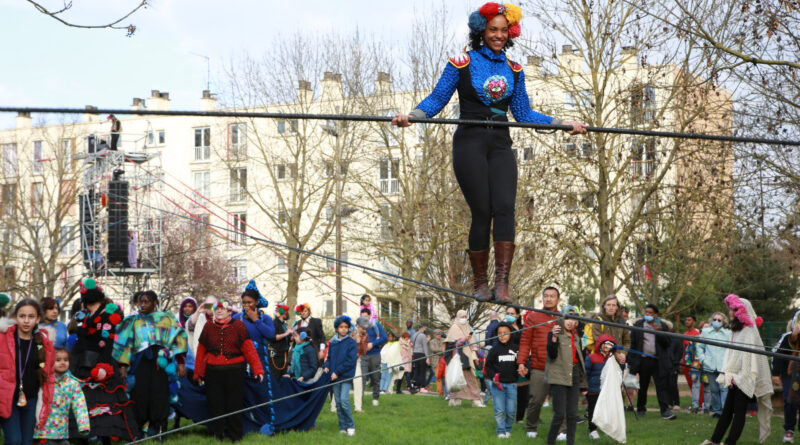 Tightrope walker, a black woman wearing blue clothes and a big smile, performs in Auch, France. Part of the Traversée show at CIRCa 2022