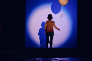 In a Circus Monti show, the spotlight falls on female clown Estelle Beugin, who carries a balloon and faces the stage wall