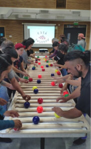 A functional juggling workshop, held by Esta Pasando at Chile's CECREA cultural center. On either side of a long table, a group of mostly young adults tries out a functional juggling board