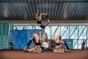 Four acrobats perform in Esplanade - Theatre on the Bay for the Flipside 2023 circus festival. This show involves acrobats bending, posing, and balancing on boxes covered with maps