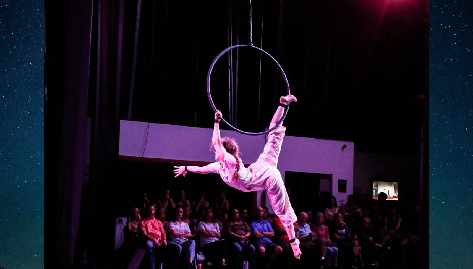 American female acrobat Veronika Agle reaching out to the crowd in her Lyra/aerial hoop routine at San Diego Circus Festival 2023