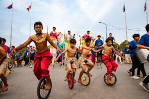 Cambodian unicyclists, four in a line, wear face and body paint and take part in the street parade of the Tini-Tinou Festival, held by Phare Circus